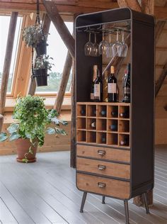 a tall wooden cabinet with wine glasses on it's doors and shelves next to a potted plant