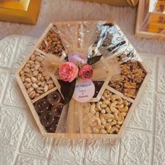 a wooden tray filled with nuts and flowers on top of a white tablecloth covered floor