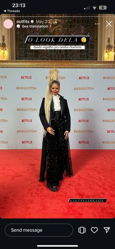 a woman standing on a red carpet wearing a long black dress and headpieces