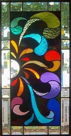 a stained glass window with colorful swirls and leaves in the center, on a sunny day