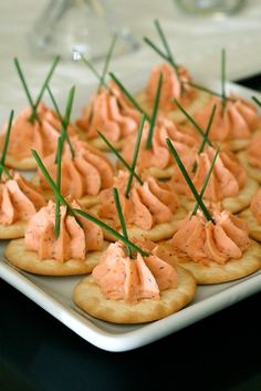 small crackers with cream cheese and chives are on a white plate, ready to be eaten