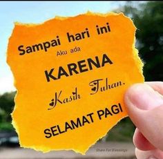 someone holding up a piece of yellow paper with the words selamat pagi on it