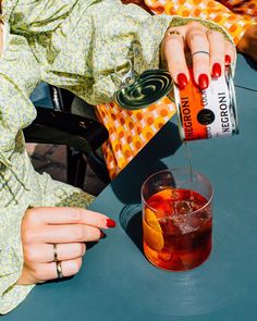 a woman is pouring an orange juice into a glass on a blue table with other people