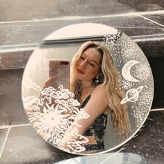 a woman taking a selfie in front of a mirror with an intricate design on it