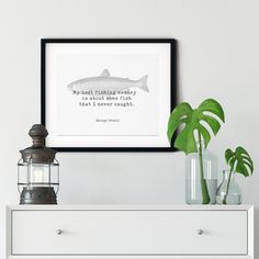 a white dresser with a black framed print on it and a potted plant next to it