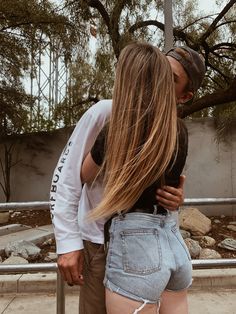 a man and woman kissing in front of a fence