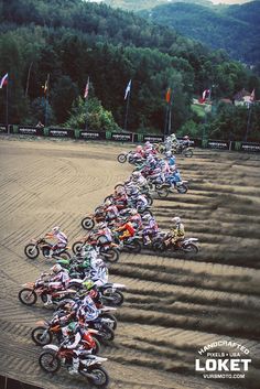 a group of people riding motorcycles on top of a dirt field