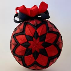 a red and black ornament with a bow on top