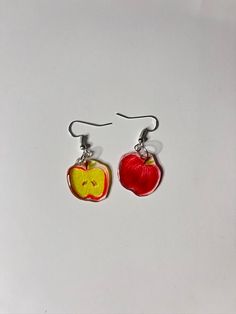 the earrings are made out of glass and have an apple on them with a smiley face