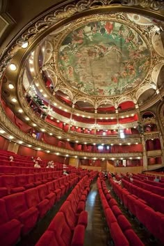 an auditorium with red seats and a painted ceiling