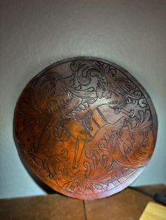 a decorative metal plate sitting on top of a wooden table next to a white wall