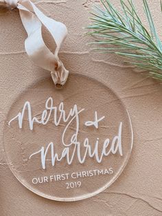 a glass ornament with the words merry and married on it next to a pine branch