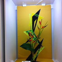 a vase with flowers in it sitting on a shelf next to a ribbon and sign