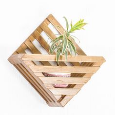 a wooden planter with a potted plant in it hanging from the side of a wall