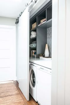 a washer and dryer in a room with white walls, wood flooring and cabinets