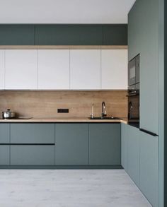 an empty kitchen with white and green cabinets