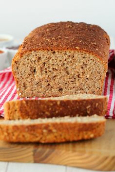 a loaf of whole wheat bread sitting on top of a wooden cutting board next to a cup of coffee