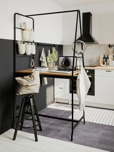 a black and white kitchen with stools next to the counter top, pot rack on the wall