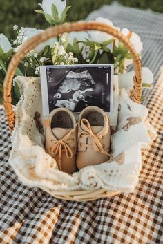 a basket filled with baby's shoes sitting on top of a table next to flowers