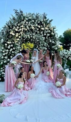 a group of bridesmaids posing for a photo in front of a flower covered tree