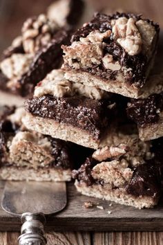 chocolate and walnut bars stacked on top of each other next to a spatula with a knife