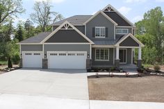 a large gray house with two garages on the front and one car door open