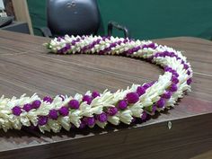 a purple and white flower lei on a wooden table