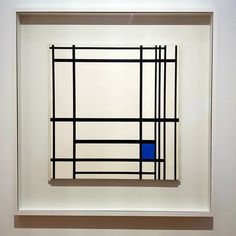 an abstract painting with black and blue squares in a white frame hanging on the wall