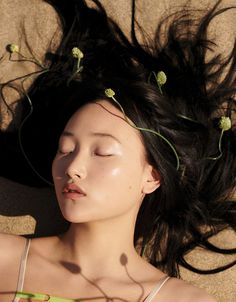 a woman laying on the ground with her eyes closed and hair blowing in the wind