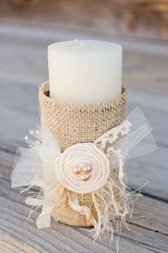 a white candle sitting on top of a wooden table next to a burlock