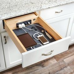 an open drawer in a kitchen filled with electronics and gadgets on top of a counter