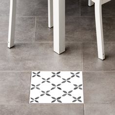 a white table and chair sitting next to each other on a floor with a black and white pattern