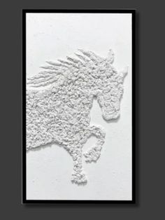 Textured white relief sculpture of a horse mid-gallop on a rectangular canvas. The dynamic pose conveys movement and energy. Black frame, neutral backdrop.