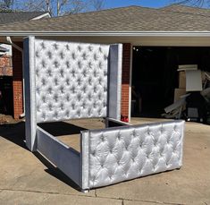 an upholstered bed frame is in front of a house with a garage behind it