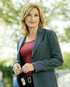 a woman in a business suit is holding her hand on her pocket and looking at the camera