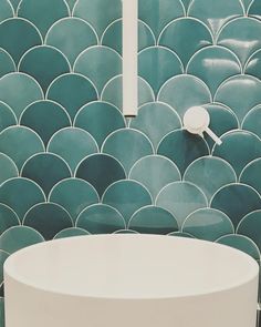 a white sink sitting under a mirror next to a green tiled wall with scallops on it