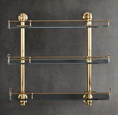 an antique brass and glass shelf with three shelves on each side, against a gray wall