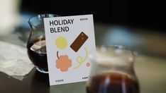 a glass filled with liquid sitting on top of a table next to a sign that says holiday blend