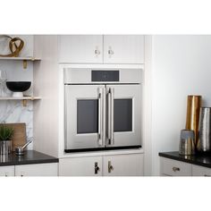 a double oven built into the wall in a kitchen with white cabinets and black counter tops