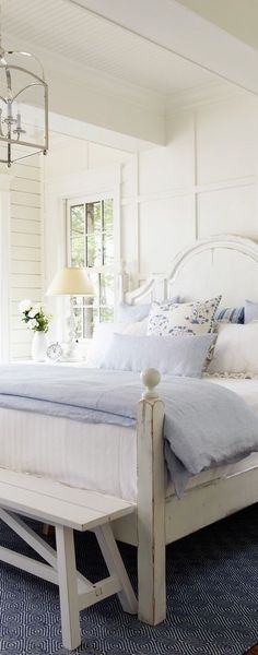 a white bed sitting on top of a wooden floor next to a blue and white rug