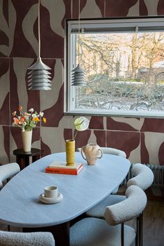 a dining room table with two chairs and a vase on top of it next to a window