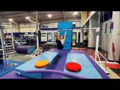 a person is doing tricks on a trampoline in a gym with other equipment