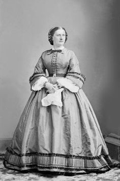 an old black and white photo of a woman in a dress