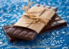 chocolate bars wrapped in brown paper and tied with twine on blue tablecloth, closeup