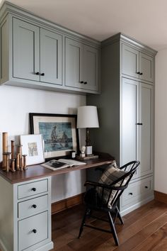 a desk with a chair, lamp and pictures on the wall in front of it