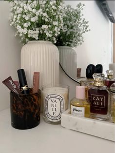 a white vase filled with lots of different types of perfumes on top of a counter