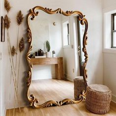 a large gold mirror sitting on top of a hard wood floor next to a window