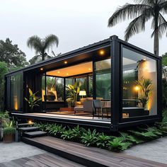 a house made out of shipping containers sitting on top of a wooden deck next to palm trees