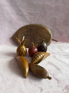 an assortment of wooden objects sitting on top of a white cloth covered table next to a bowl