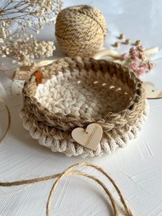 a basket with a heart on it sitting next to some twine and other items